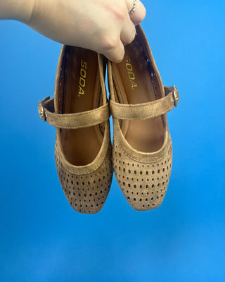 Brown Faux Suede Mary Jeane One Strap Mule held up against a solid blue background. 