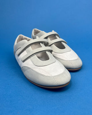 Ivory Faux Suede Mary Jane Double Strap Flat held up against a solid blue background. 