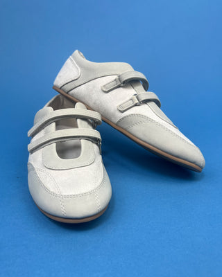 Ivory Faux Suede Mary Jane Double Strap Flat held up against a solid blue background. 