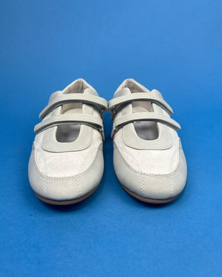 Ivory Faux Suede Mary Jane Double Strap Flat held up against a solid blue background. 