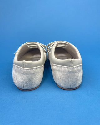 Ivory Faux Suede Mary Jane Double Strap Flat held up against a solid blue background. 