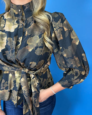 Black floral blouse featuring a high neckline, button-front detail, three-quarter puff sleeves, and a coordinating waist tie for a flattering finish.