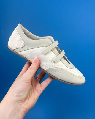 Ivory Faux Suede Mary Jane Double Strap Flat held up against a solid blue background. 