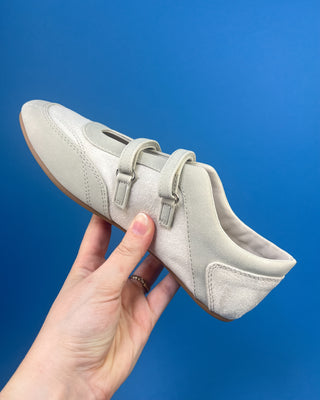 Ivory Faux Suede Mary Jane Double Strap Flat held up against a solid blue background. 