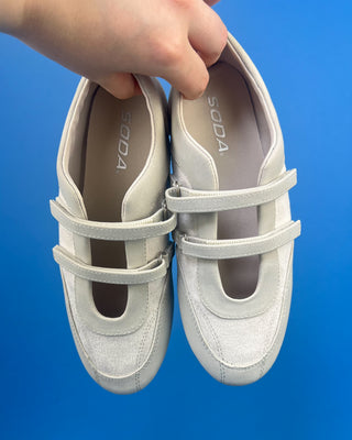 Ivory Faux Suede Mary Jane Double Strap Flat held up against a solid blue background. 