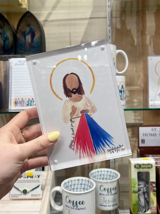 Hand holding a card with a religious figure illustration in a store setting