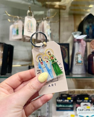 Keychain with artistic depiction of a family on a tag held by a hand in a store setting.