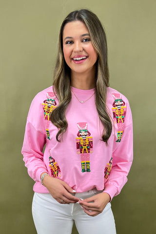 Woman wearing a pink sweatshirt with colorful designs on a green background