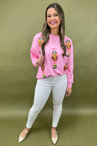 Woman wearing a pink sweatshirt with colorful designs, holding lollipops, on a green background