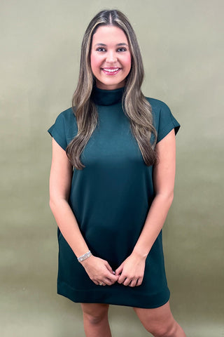 Woman wearing a green dress against a beige background