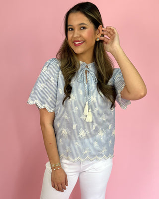 Woman wearing a blue and white striped blouse with a pink background