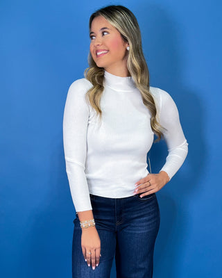 White ribbed mock neck top featuring long sleeves, a fitted silhouette, soft stretch texture, and a clean, classic look.