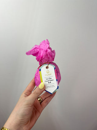 Hand holding a pink decorative item with a label against a plain background