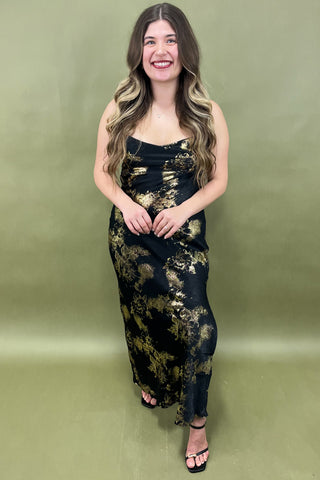 Woman wearing a black and gold dress against a green background