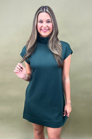 Woman wearing a teal dress against a beige background