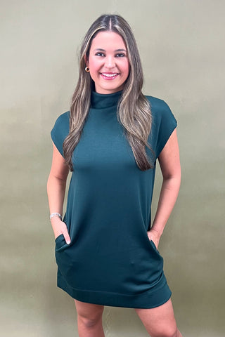 Woman wearing a teal dress against a plain background