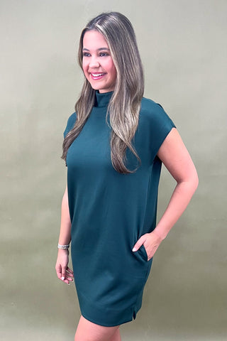 Woman wearing a teal dress against a plain background
