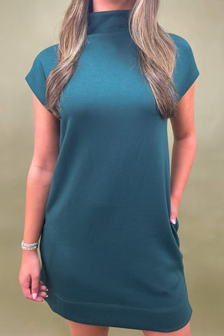 Teal dress worn by a person against a beige background