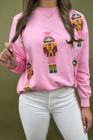 Person wearing a pink sweatshirt with colorful robot design on a green background