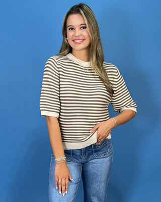 a beige and dark brown horizontally striped short-sleeve top with a curved hem, paired with blue jeans and metallic gold flats