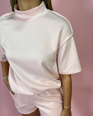 Pink outfit with a high neckline on a pink background