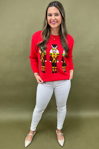Woman wearing a red sweater with nutcracker design against a green background