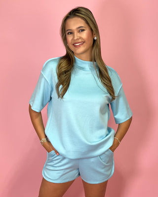 Woman wearing a light blue outfit against a pink background