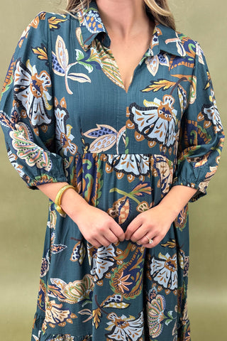 Woman wearing a long floral dress with a green background
