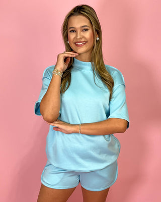 Woman wearing a light blue outfit against a pink background