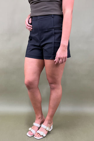 Person wearing black shorts and white sandals on a plain background