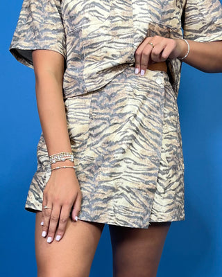 A woman modeling a short-sleeve collared shirt dress with a beige and gray zebra print