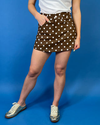 Brown and white polka dot mini skirt featuring a high-rise fit, classic five-pocket styling, button-and-zip closure, and a structured A-line silhouette.