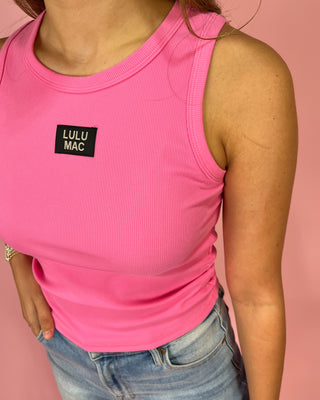 Person wearing a pink tank top with 'LULU MAC' logo against a pink background