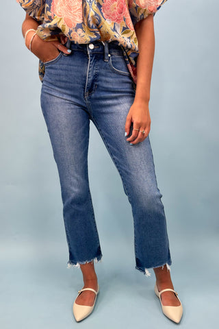 Person wearing blue jeans and a floral top on a light gray background