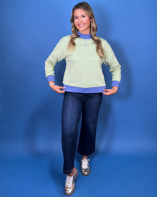 a light green and white striped long-sleeve crewneck sweater with a solid blue mock neck collar, cuff