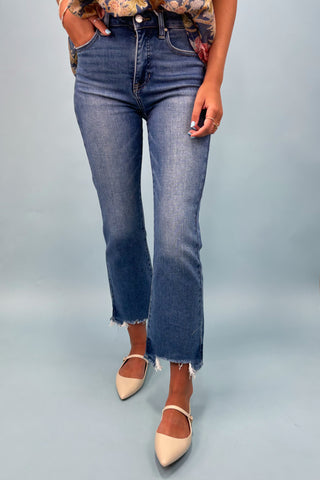 Person wearing blue jeans and beige shoes on a gray background
