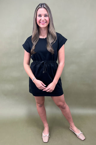 Woman wearing a black dress against a plain background