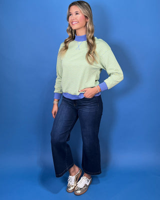 a light green and white striped long-sleeve crewneck sweater with a solid blue mock neck collar, cuff