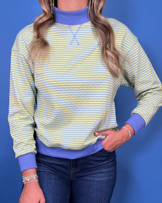 a light green and white striped long-sleeve crewneck sweater with a solid blue mock neck collar, cuff
