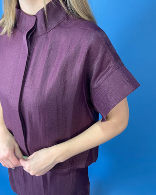Burgundy two-piece skirt set featuring a relaxed short-sleeve top with a high neckline and a coordinating structured mini skirt.