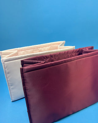 Case Mate Tote Bag Organizer Inserts in Colors Mulberry, Ballet Pink, & French Vanilla displayed against a slid blue background. 