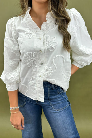 White embroidered blouse with blue jeans on a plain background