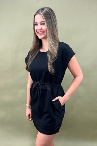 Woman wearing a black dress against a plain background