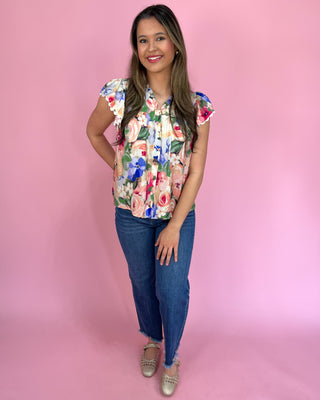 Woman wearing a floral top and jeans on a pink background