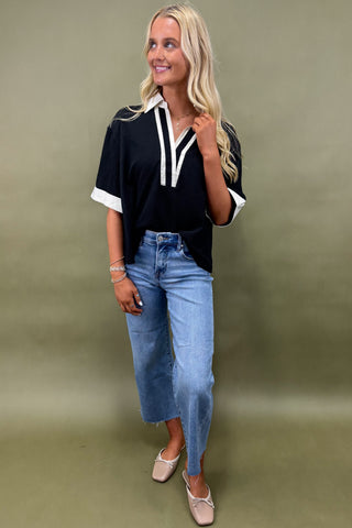 Woman wearing a black and white top with blue jeans on a green background