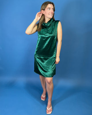 Emerald green satin dress featuring a sleeveless silhouette, draped cowl neckline, subtle sheen, and relaxed A-line fit.