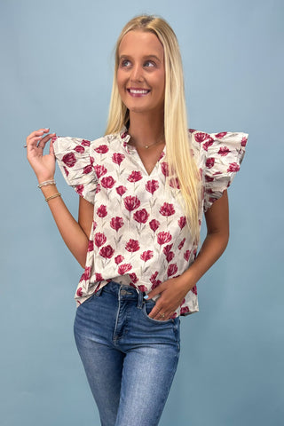 Woman wearing a floral blouse and jeans against a light blue background