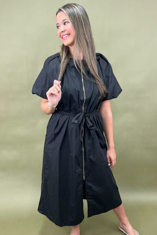 Woman wearing a black dress against a green background