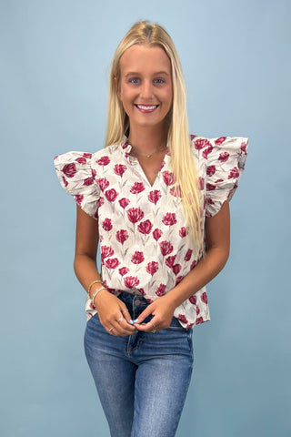 Woman wearing a floral blouse with ruffled sleeves against a blue background