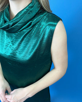 Emerald green satin dress featuring a sleeveless silhouette, draped cowl neckline, subtle sheen, and relaxed A-line fit.